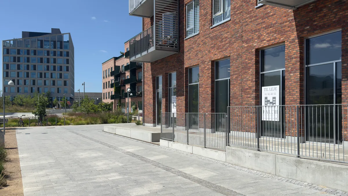 Lejlighedsbygning med moderne design og glasvinduer samt møbeludsalgsskilt på facaden