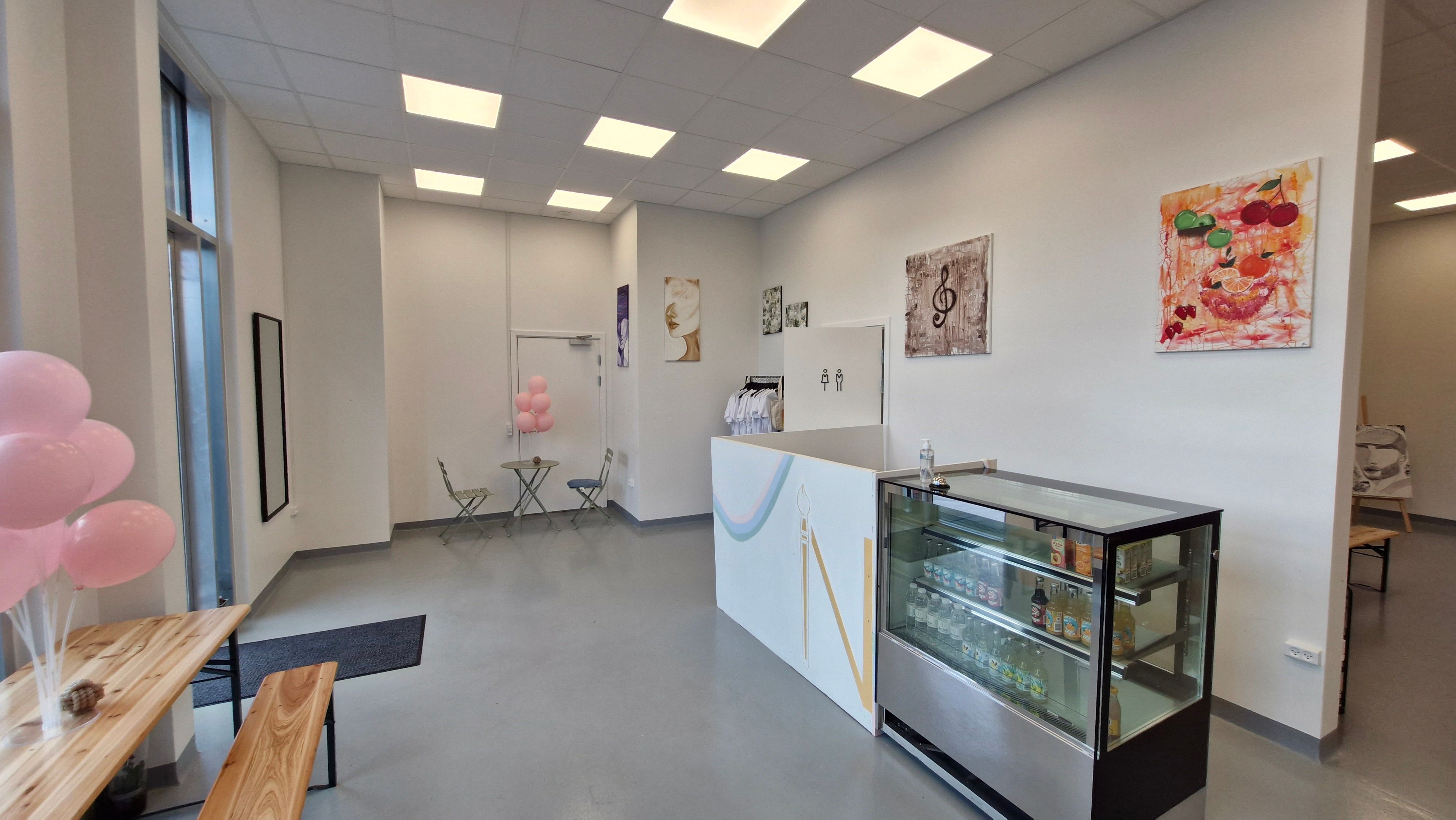 Lejlighed med lyse loftslampe og lysegule vægge med malerier, smukt pyntet med pink balloner og lyse stole i baren.