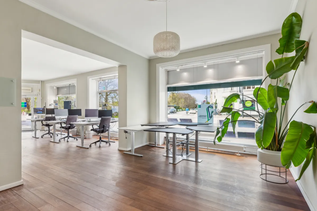 Et moderne og pænt lejemål med lyse vinduer og højt til loftet. Bord og stole er placeret rundt om i rummet, og der er en