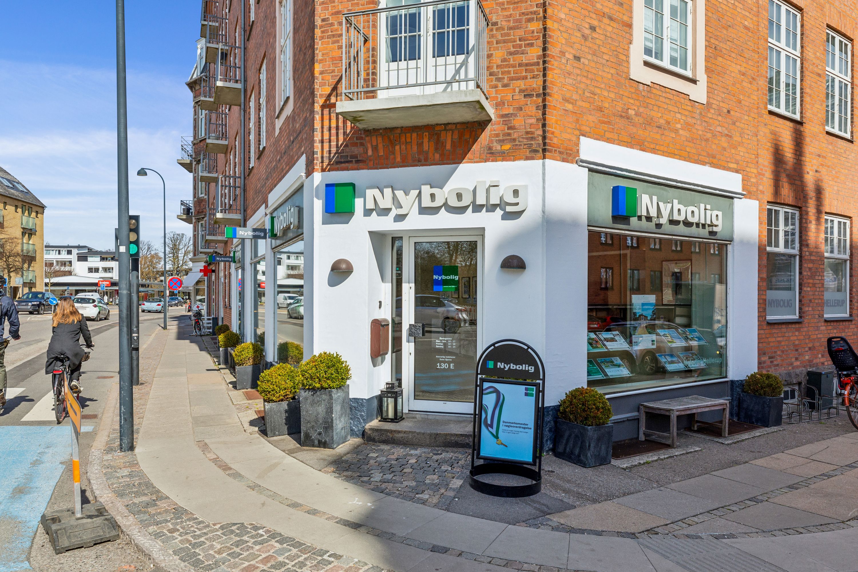 Lejemålet Nyboligt ligger på Strandvejen 130E i Hellerup med en hvid facade, røde mursten og vinduer. Lejemålet har glasdøre
