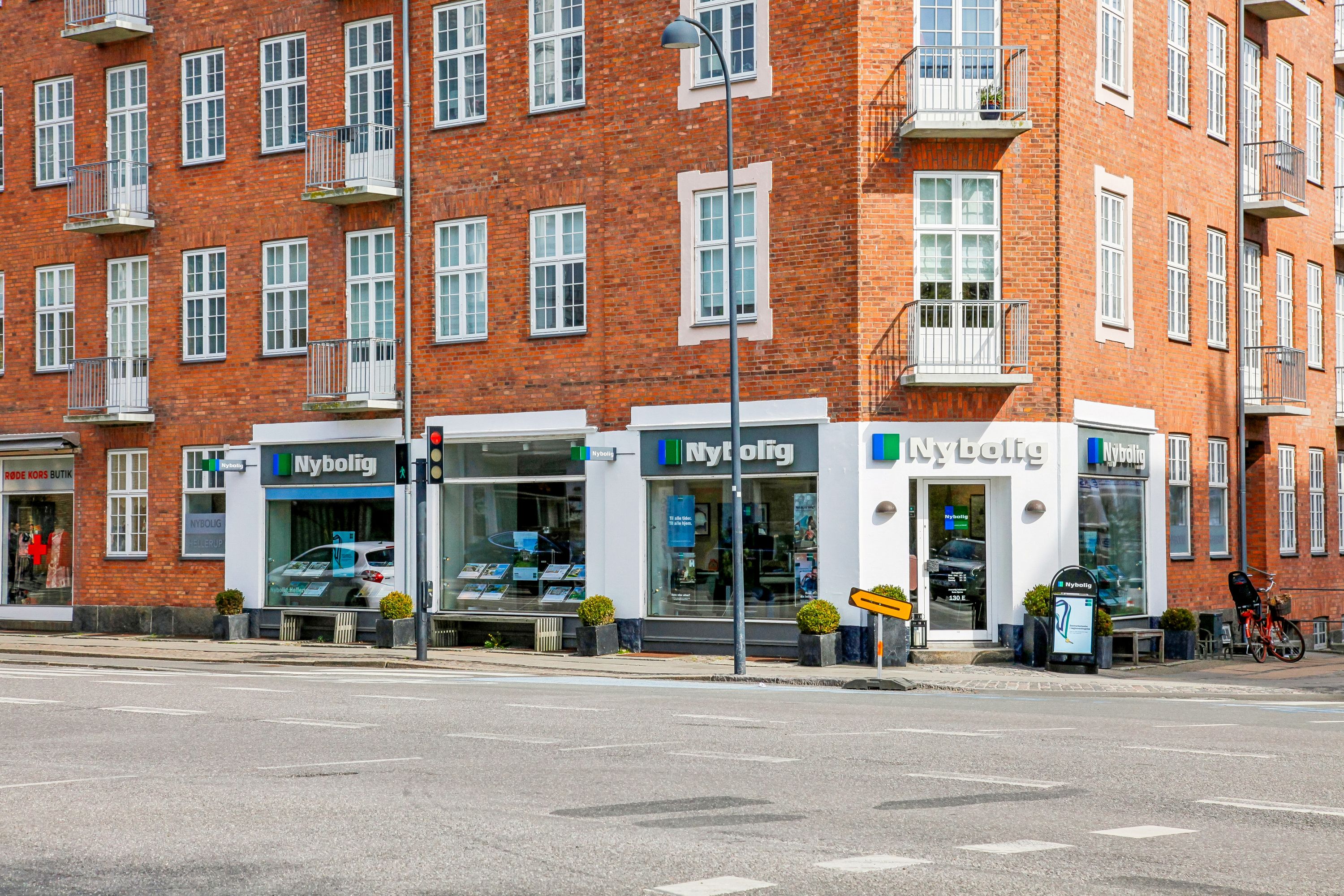 Moderne lejemål på Strandvejen med plantager og gult skilt med pil, sammen med en rødmærket cykel og gågade