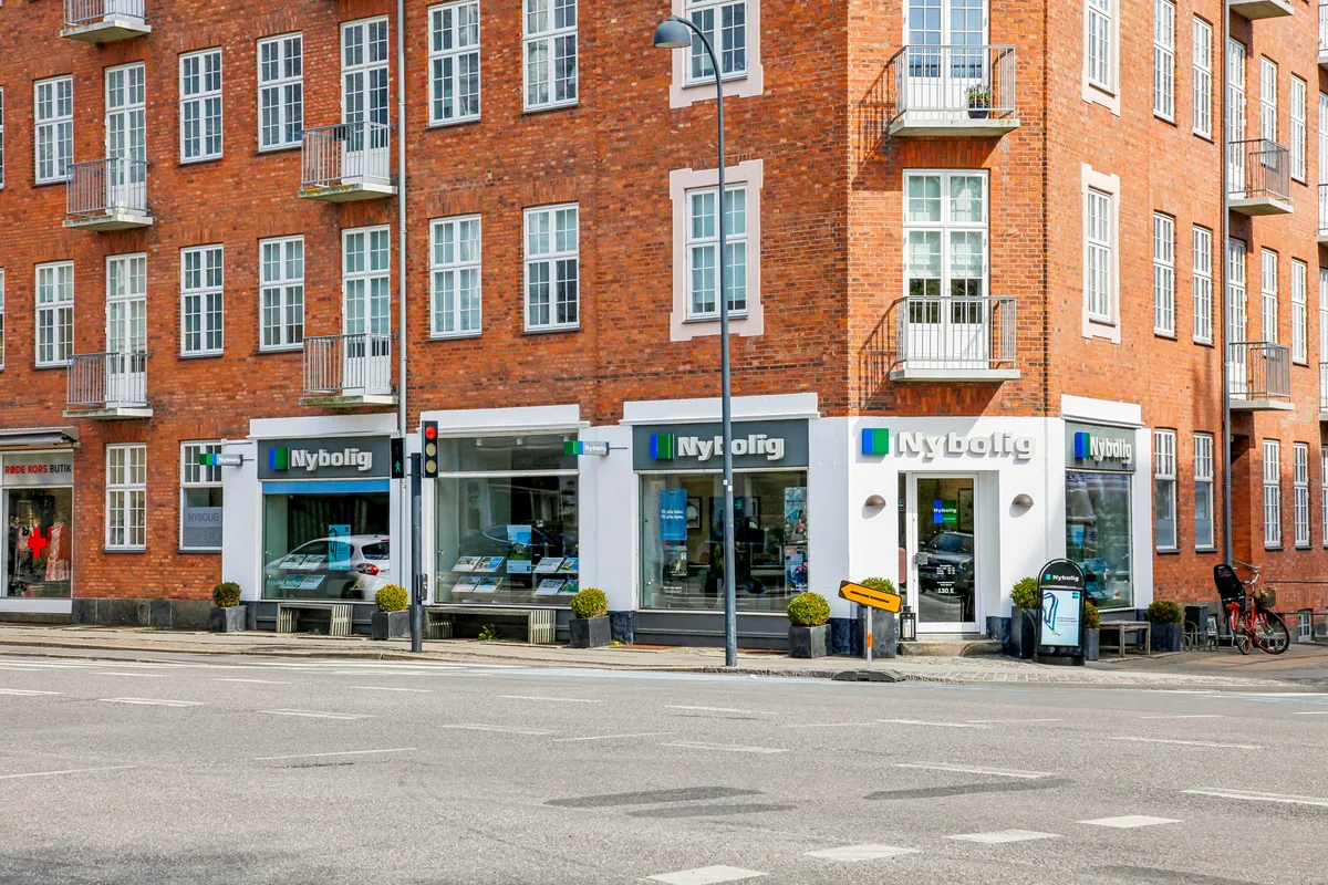 Moderne lejemål på Strandvejen med plantager og gult skilt med pil, sammen med en rødmærket cykel og gågade
