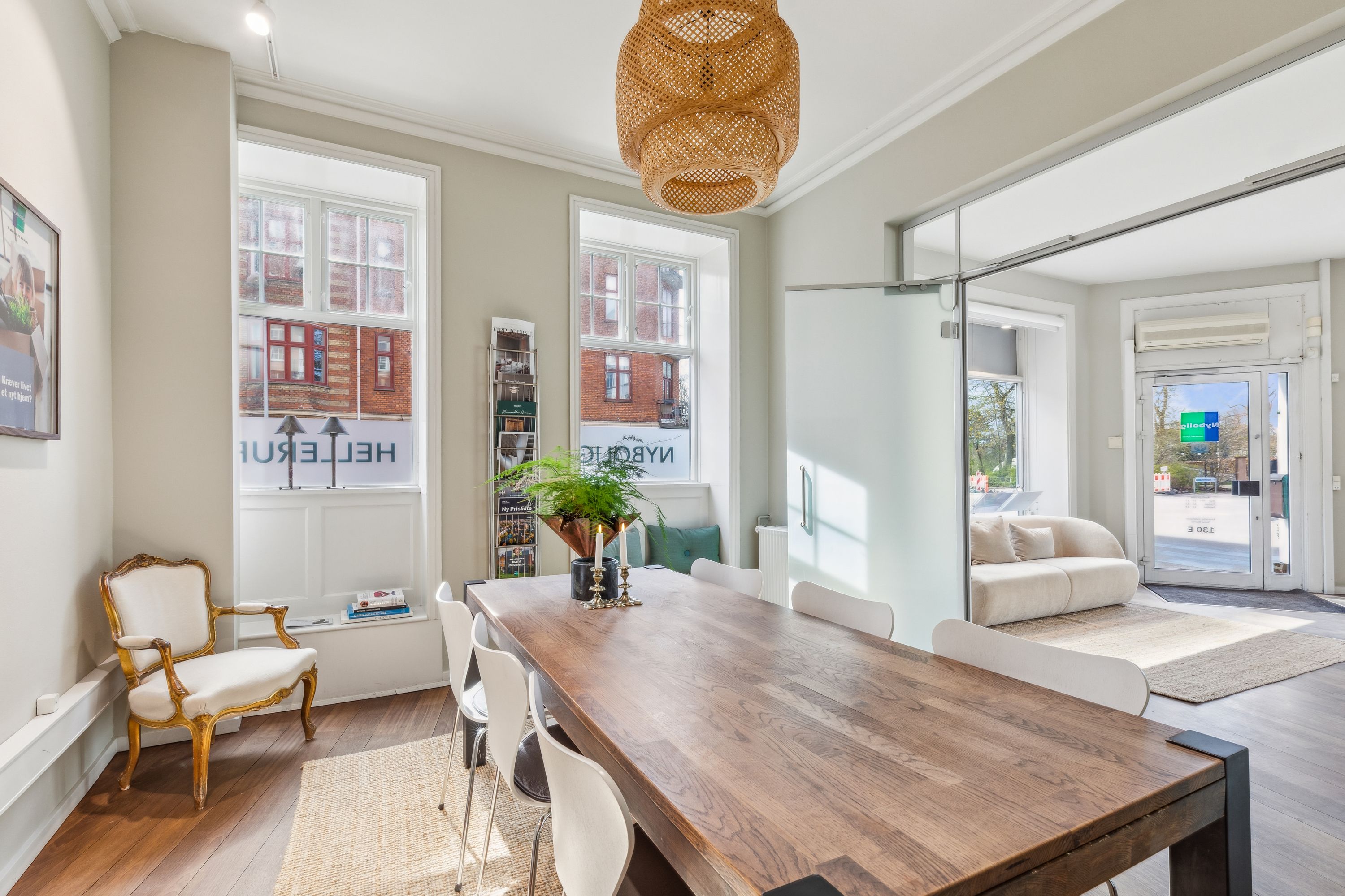 Lys, luftig stue med lyse, lysegule vægge og lyse trægulve. Langt træspisebord med hvide stole og puder. Komplet med