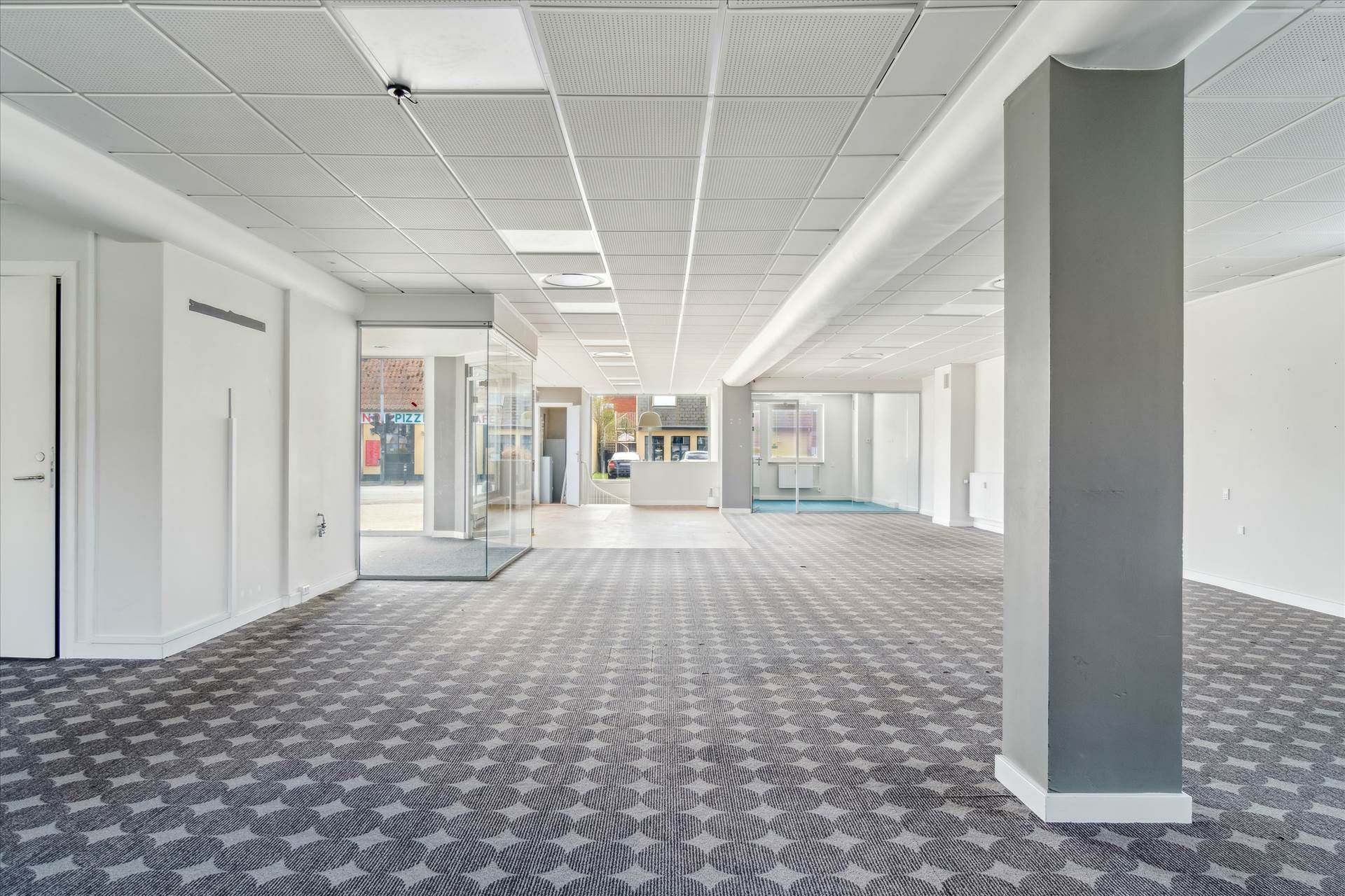 Store tomme lokaler med lyse lofter og gulvbelægning med et rektangulært mønster og hjørneplacering i et erhvervsområde