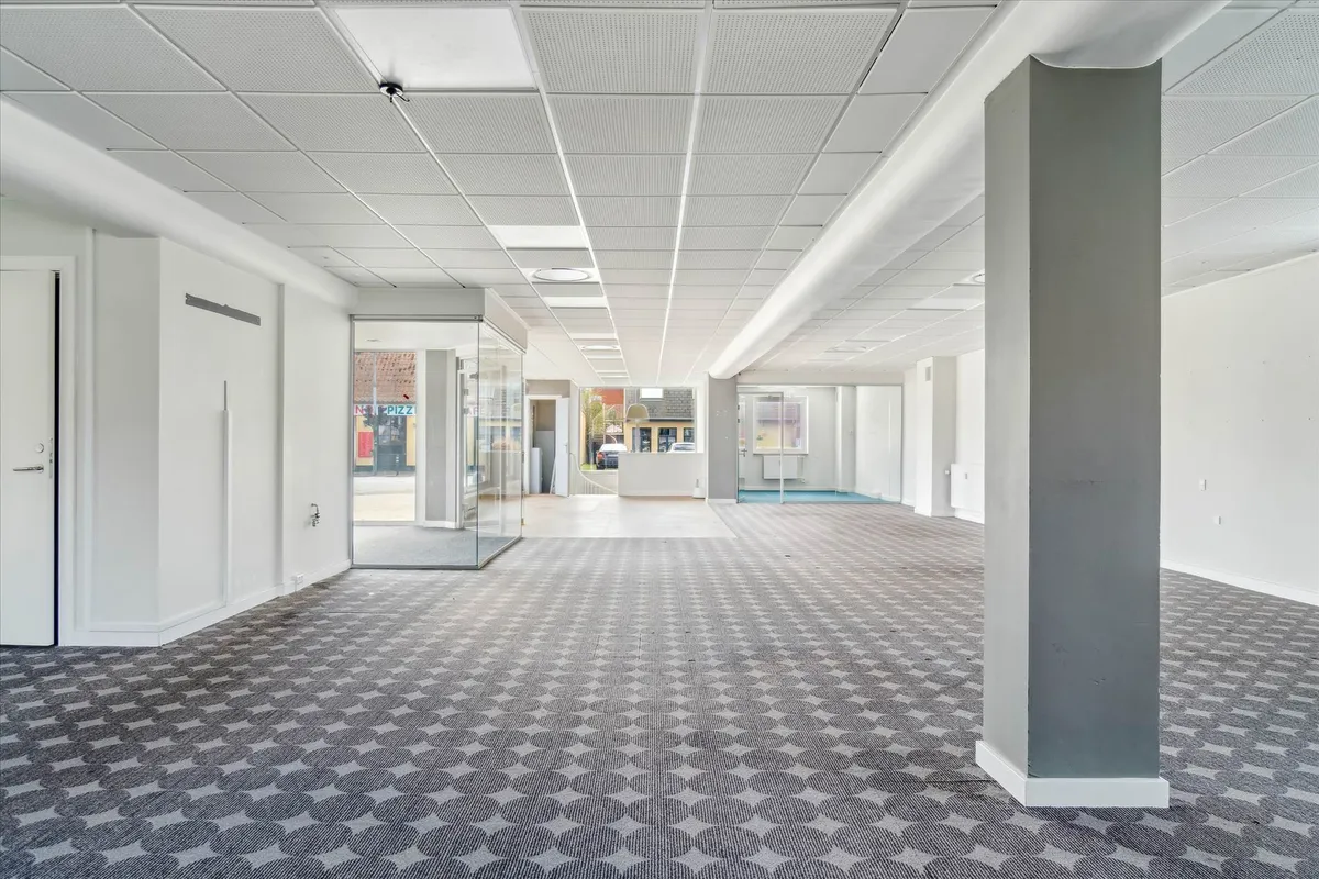 Store tomme lokaler med lyse lofter og gulvbelægning med et rektangulært mønster og hjørneplacering i et erhvervsområde