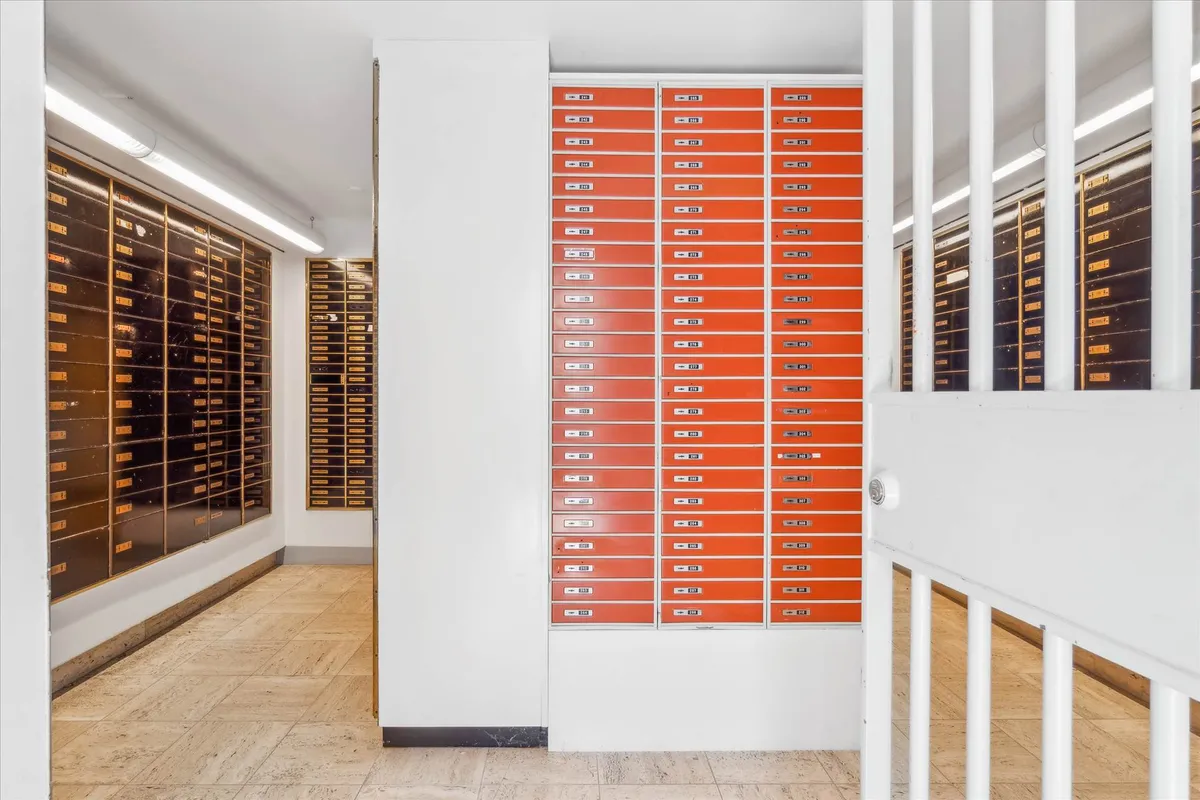 Man kan se en lille række orange farvede hængslede kabinetter med numre og håndtag til åbning og lukning af hver kabinet.