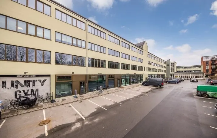 Kontor i Frederiksberg med moderne udsigt, Unity Gym og parkeringsplads. Faciliteter med cykler og parkerede biler.