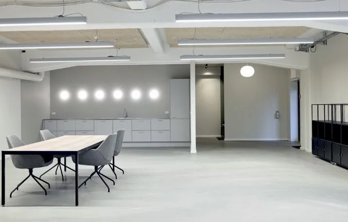 Kontorområde med moderne møbler og hvide vægge, lysekroner og lyse buer, stolpe og loft, gulv og bord