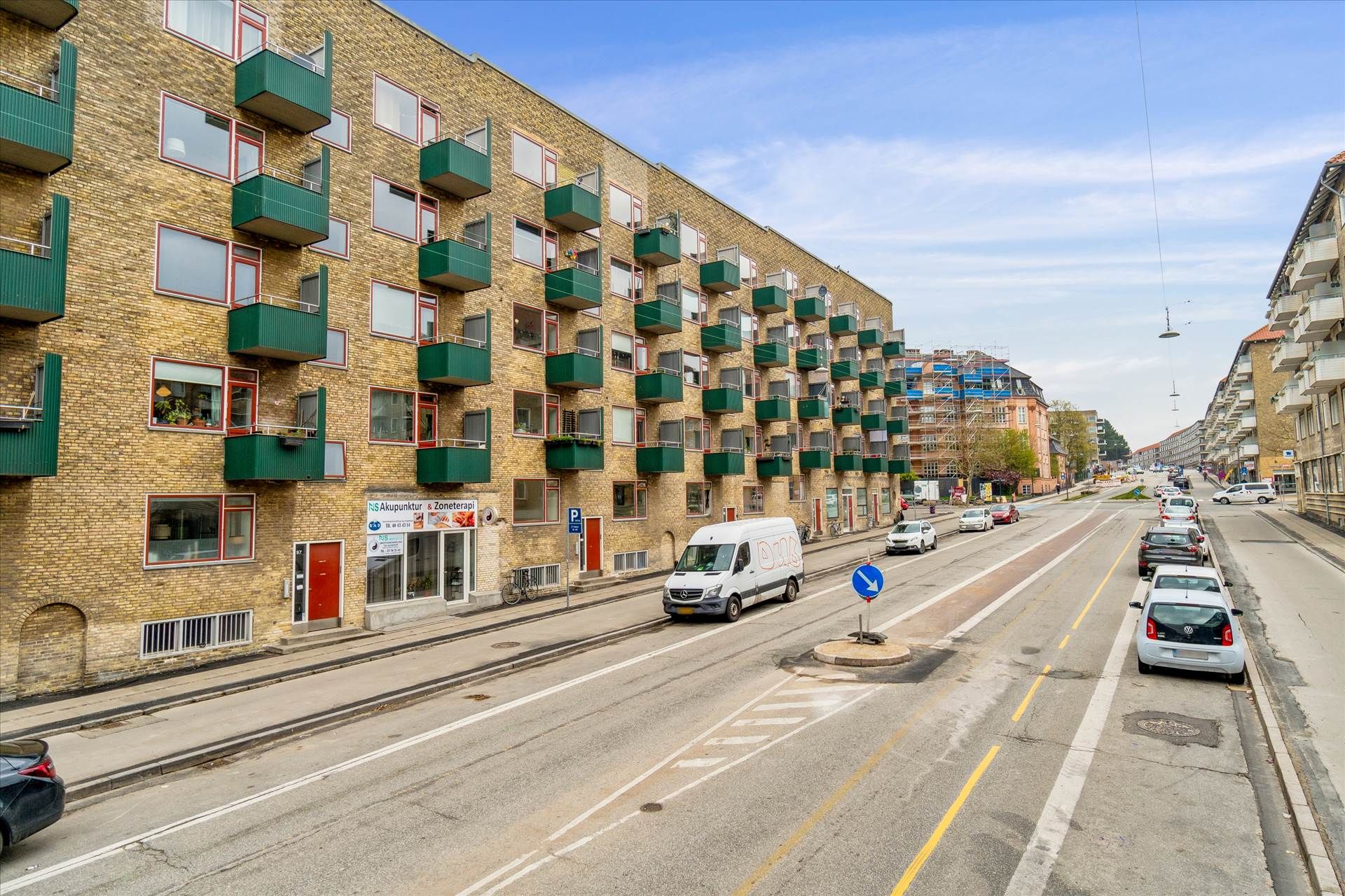 Store lejlighedsbygning med mange balkoner og parkerede biler langs Frederiksborgvej i København
