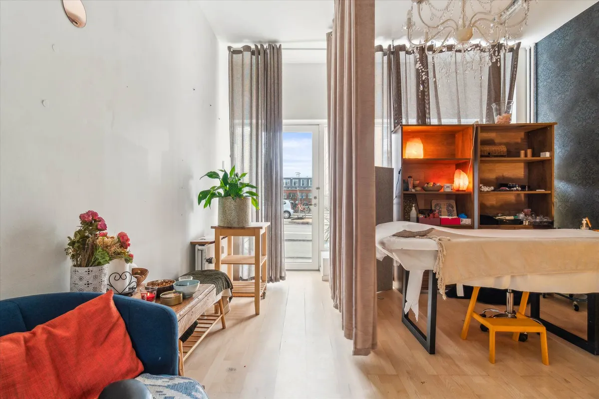 Butik med indretning, hvid sofa med pude, stueplante, masser af lyse og lyse nuancer, bord med lyse lamper og stole