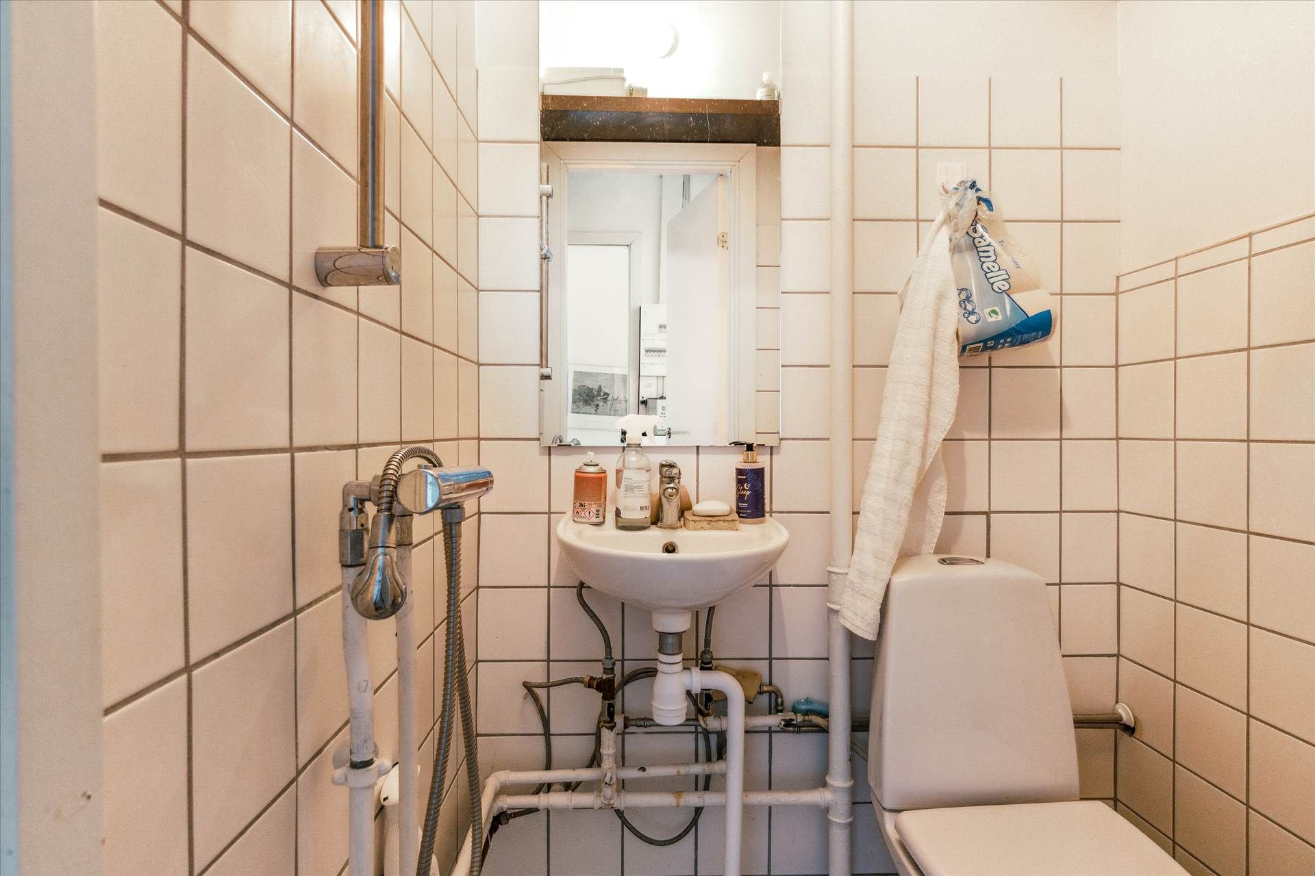 En lille badeværelse med toilet, håndvask og en håndklæde, der er hængt på væggen