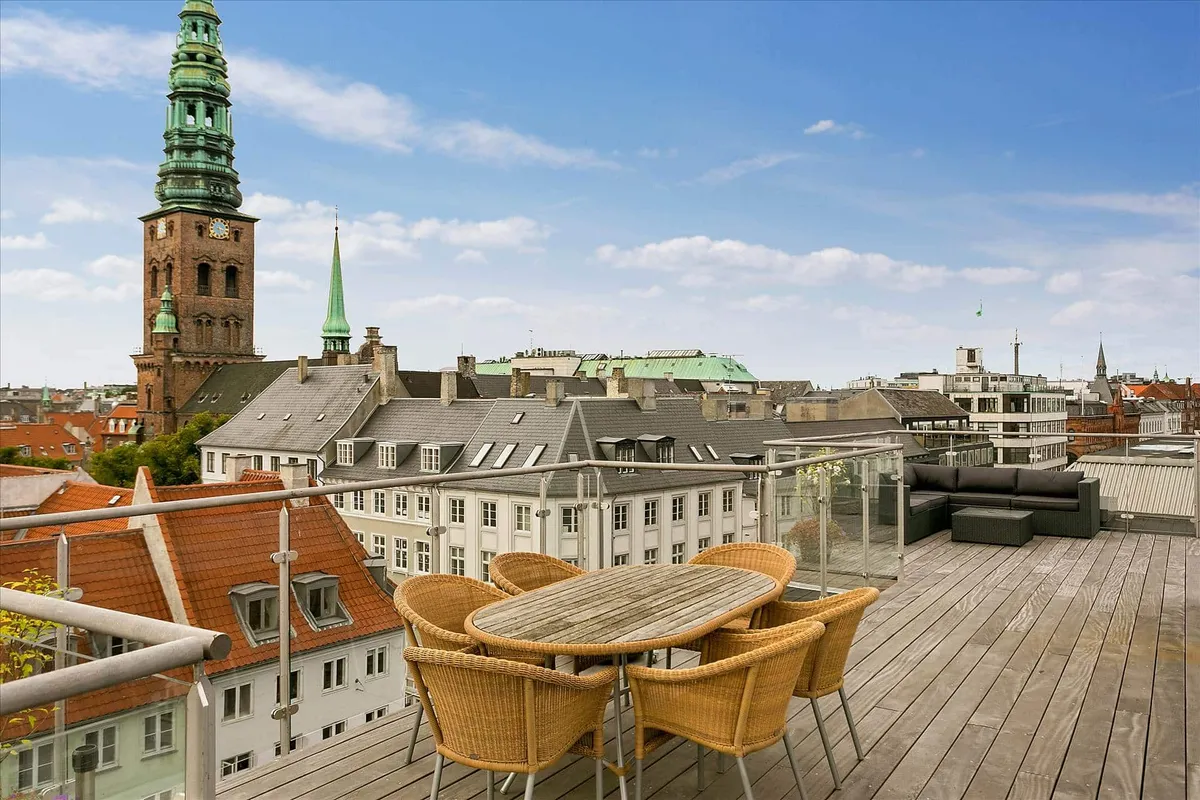 Terrasse med udsyn over Københavns middelalderby, møbler og sofa, høje bygninger og tårne i baggrunden
