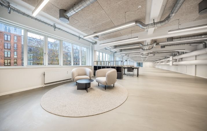 Kontorlokaler med store vinduer, lyseloft, højt til loftet, moderne møbler og beige gulvbelægning