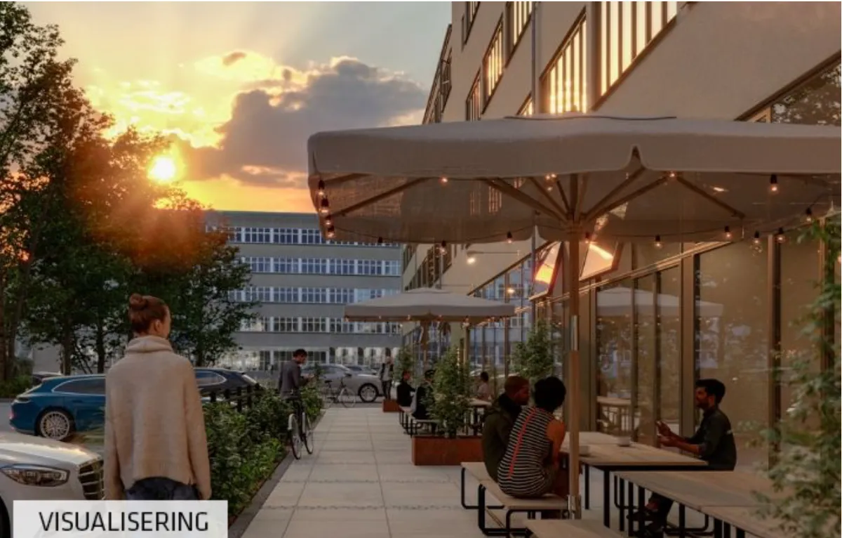 Hyggelig café med parasoller og plantager, mennesker sidder og arbejder, smukke bygninger og biler i baggrunden, lys og