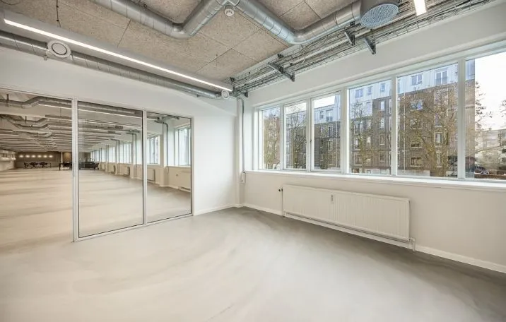 Store glasvinduer og store spejle skaber lyset og roen i denne kontorlokal. Hvidt loft og gulv med højt til loftet hænger