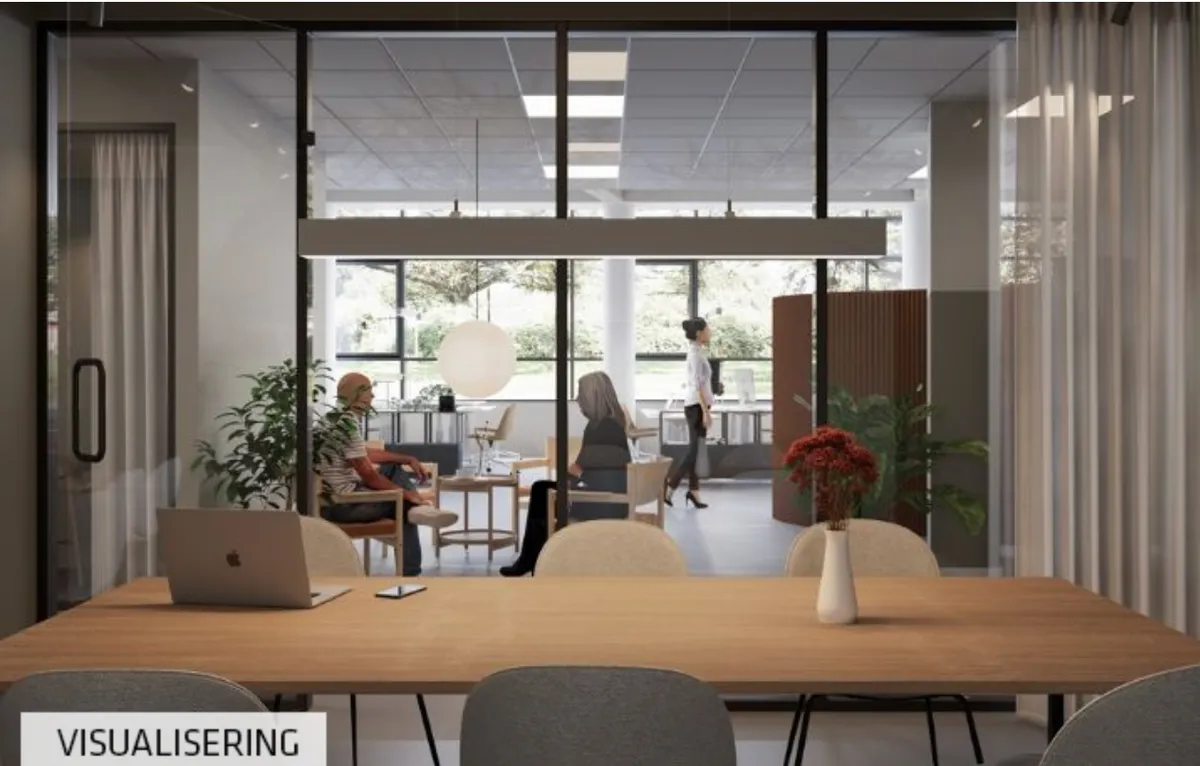 Kontorlokaler med moderne møbler, en åben indretning og lyse vinduer, hvor folk sidder og arbejder