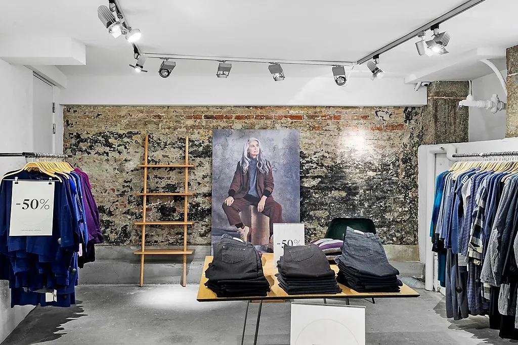 Et lager med tøj og jeans samt en rabat på 50 procent. Der er tøj på ståhylder og tøjhængere.