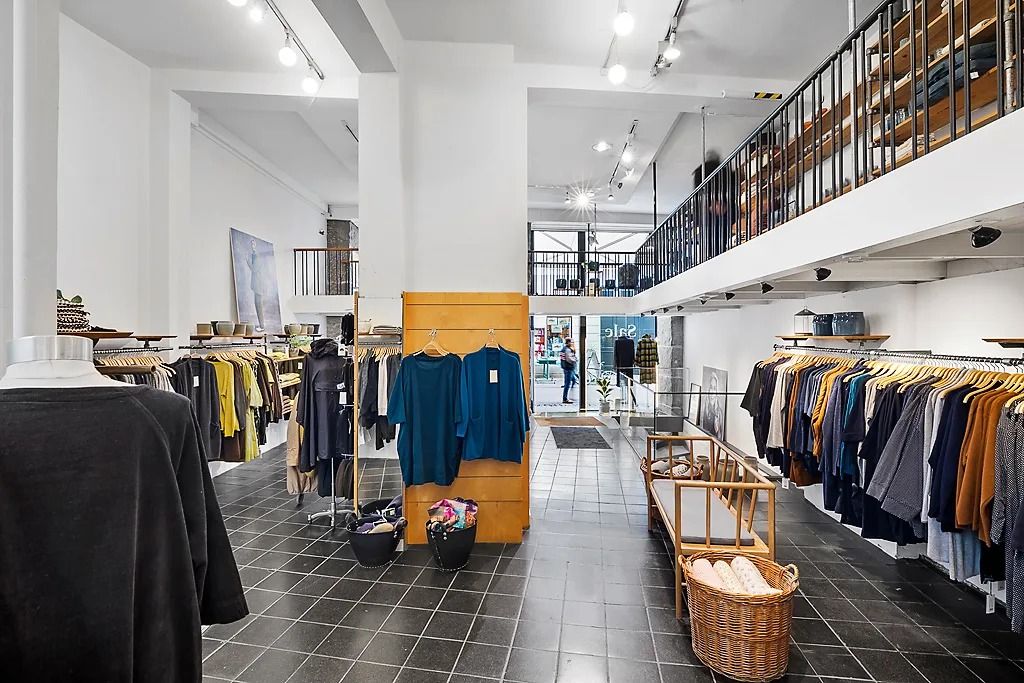 En søjle og to gulve med tøj og tilbehør i en luksuriøs butik med højloftede værelser og trægulve