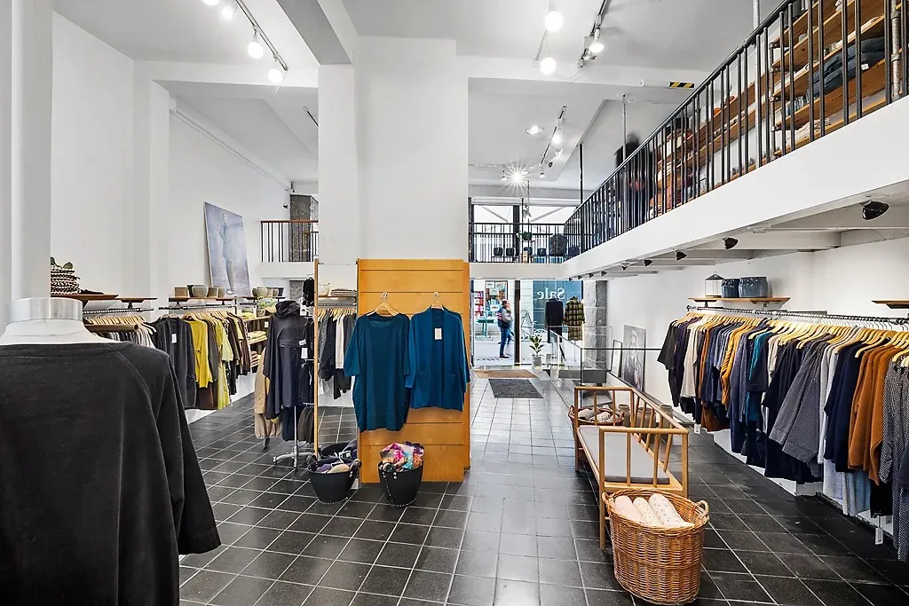 En søjle og to gulve med tøj og tilbehør i en luksuriøs butik med højloftede værelser og trægulve