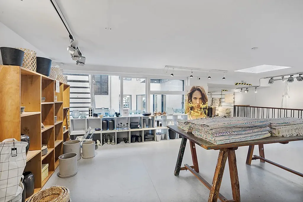 Indvendørs er der en høj hylde med tallerkener, og der er flere kurve og tekstiler på bordet