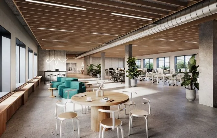 Kontorlokaler med lyse gulve, hvide stole, rundt bord og plante i hjørnet af lokalet