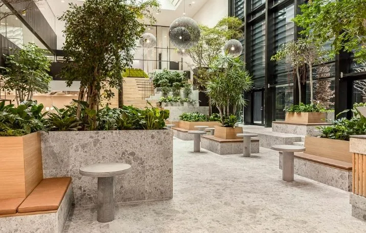 Moderne lobby med lyse loftslamper og træmøblerede bænke med kunstige planter i store træpotter