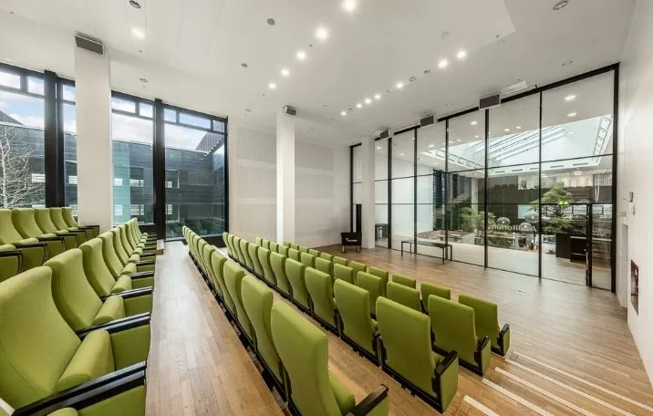 Rømmet med store glasruder og grønne stole. Elegante trægulve og moderne interiør. Minimalistisk design med lysepunkter.