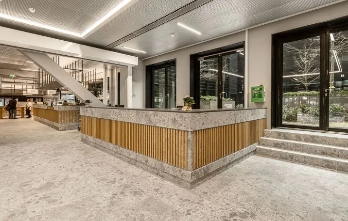 Elegant lobby med marmor og træ accenter, moderne interiør med glasdøre og indendørs planter