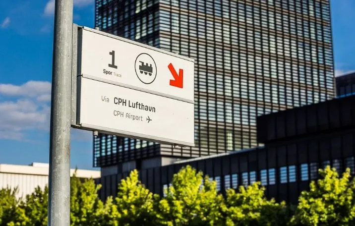 Vejledningsskilt med en rødt pil pekende opad forsporet med sporvogns- og flysymboler