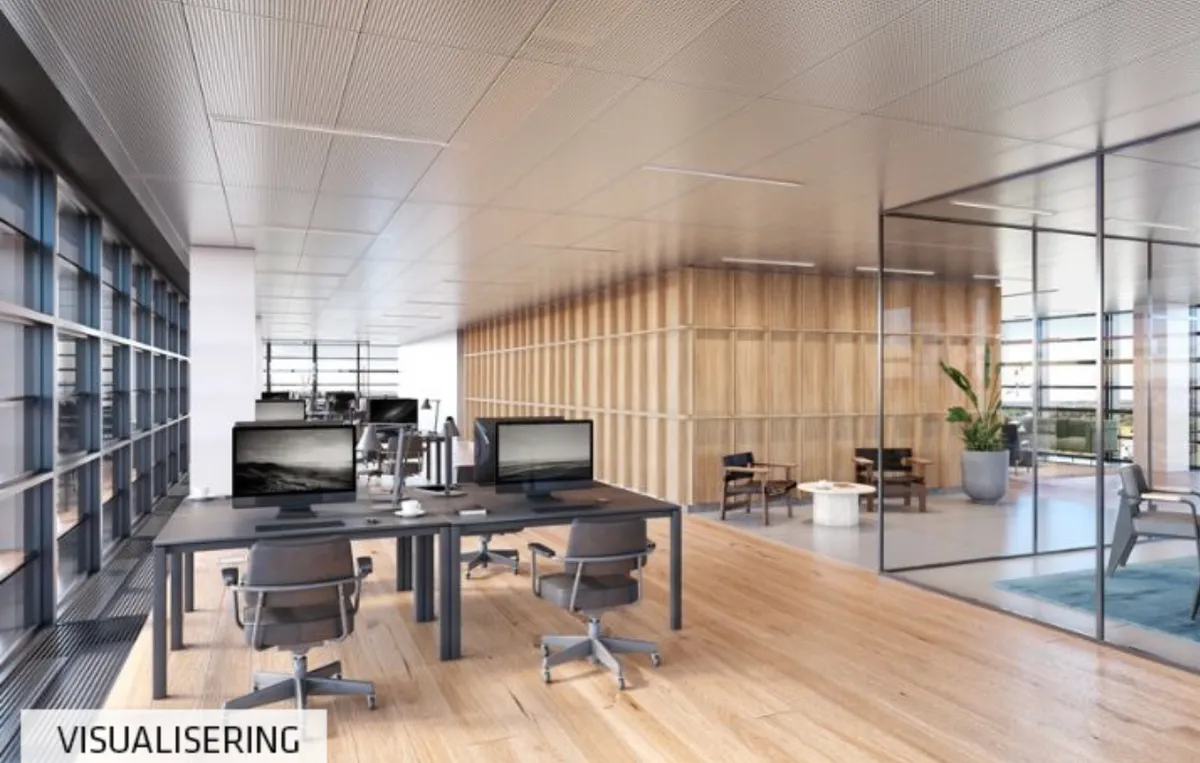 Kontorområde med moderne udsmykning og lysegule gulv. Bord med computere og stole placeret i rummet