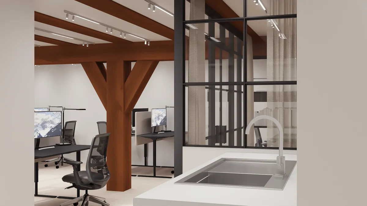 En nyrenoveret kontor med lyse loftstræer og moderne skriveborde med skærme samt en enkelt hvid vask med vandhane