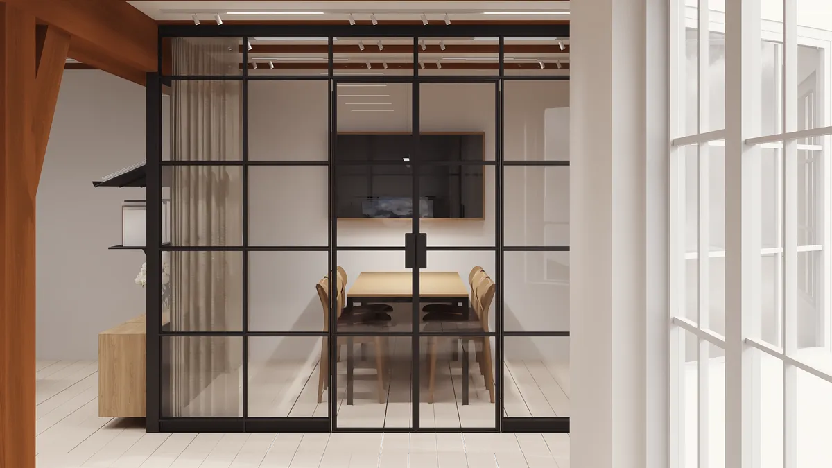 En lukket sort glasdør med rammer fører ind i et moderne kontor. Der er en bord og stole, og bag glasdøren er der en