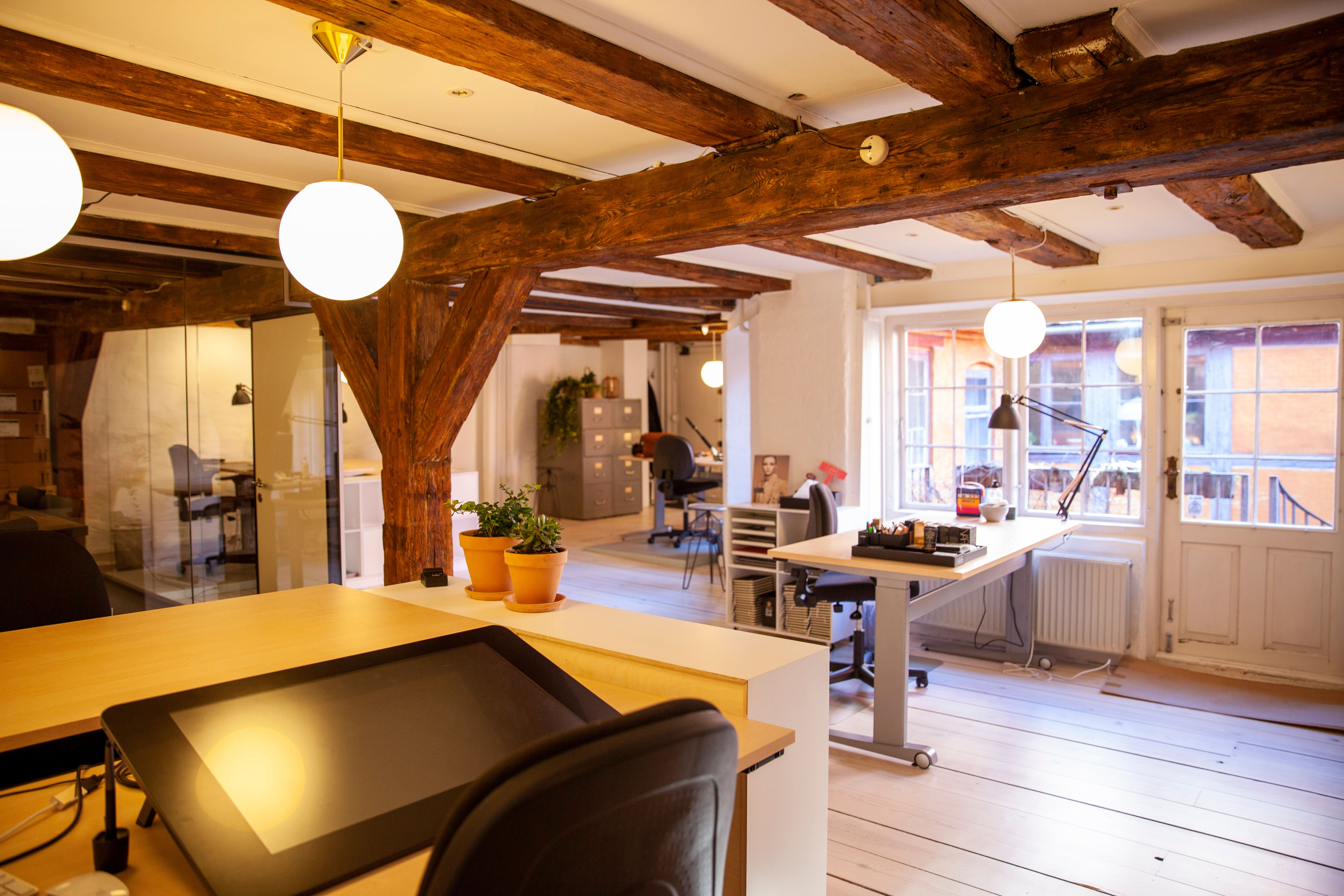 Kontor med åbent rum, gulve, skriveborde, lysekroner, lyse, plantepot, radiator, stol, skrivebordslampe, vinduer og døre