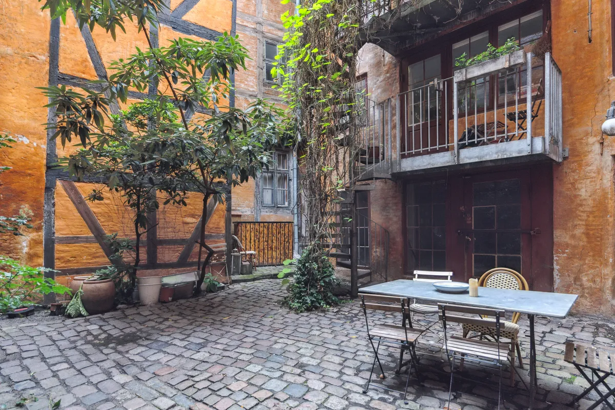 En smuk stue med gulve af skandinavisk egetræ, stolpe af brædder og et vindue med plantepot.