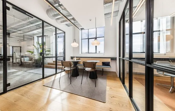 Indenfor det moderne kontor med søjler og glasvægge ser man smukke trægulve, og et moderne bord og stole samt lysekroner