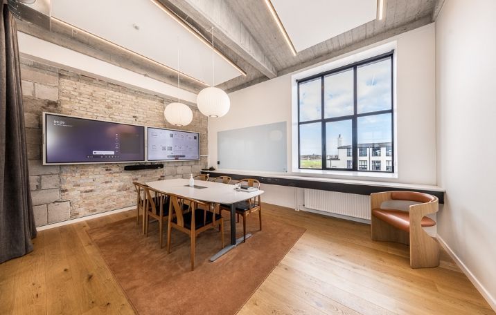 Moderne kontor med to store skærme og en stor rund borde, hvor man kan tage sæde