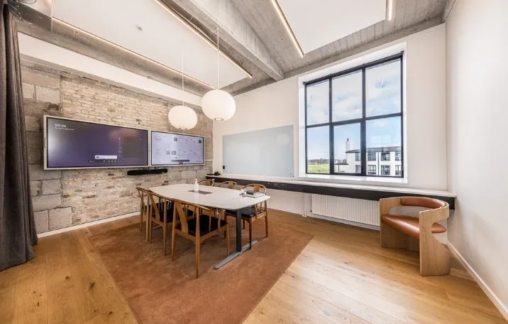 Moderne kontor med to store skærme og en stor rund borde, hvor man kan tage sæde