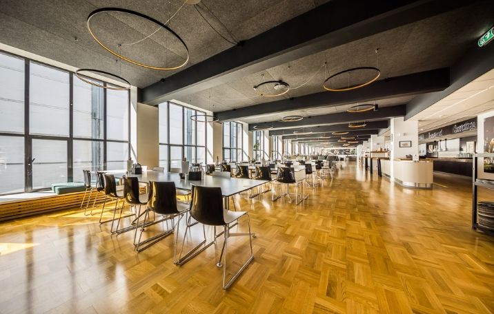 Kontor med lyse trægulve, højt loft, store glasvinduer og moderne møbler