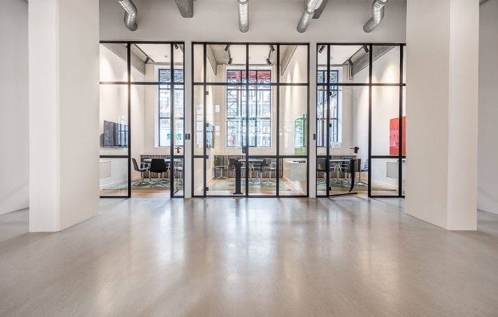 Rå fabriksstil med glasvægge og sandblæste søjler. Ingen personer. Moderne kontordesign med lyse lofter og lyse buer.