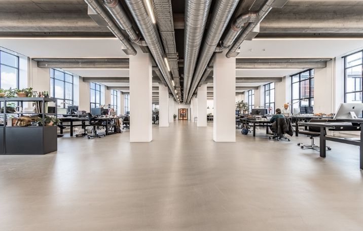 Moderne kontorrum med højt til loftet og store vinduer, sandblæste søjler og en åben rumfølelse
