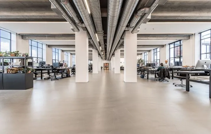 Moderne kontorrum med højt til loftet og store vinduer, sandblæste søjler og en åben rumfølelse