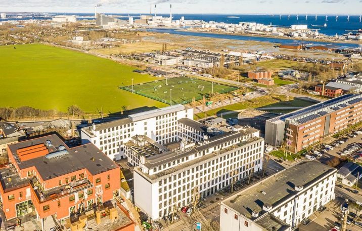 Kontorbyggeri i København med moderne arkitektur, glas og sandblæste søjler. Bygningerne er hvide med røde detaljer og