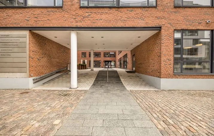 Moderne bygning med røde mursten og hvide vinduer og glasdøre og trappe foran indgang