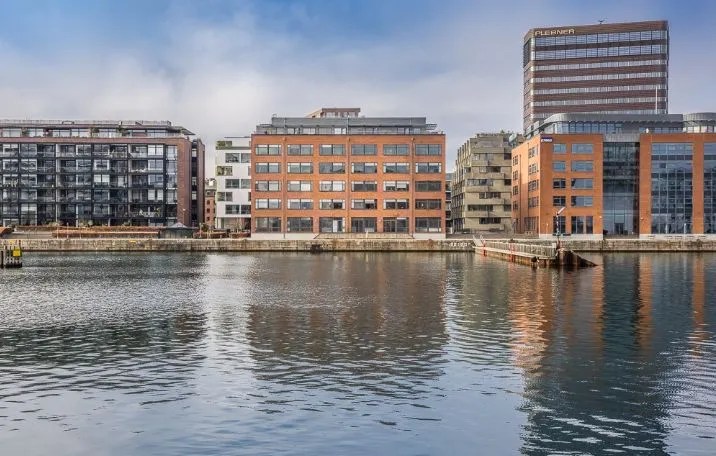 Moderne bygninger med glasvinduer og terrasser langs en vandkant i København Havnefronten