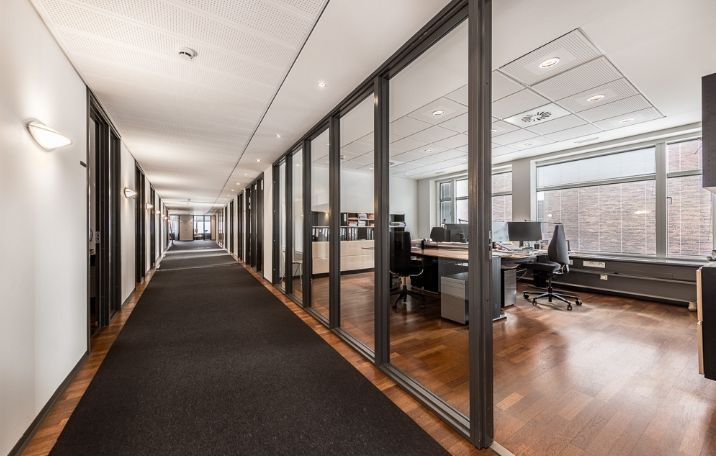 Kontorgang med gulvbelægning og glasvægge, der giver lys og åbenhed i lokalerne