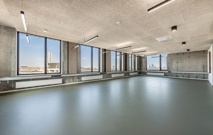 En stor lejlighed med store vinduer og lyse loftslamper, moderne gulvbelægning og store vinduer med udsigt til byens skyline