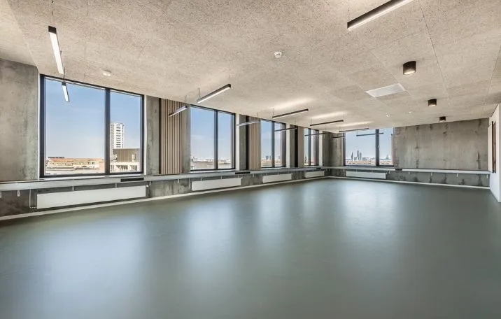 En stor lejlighed med store vinduer og lyse loftslamper, moderne gulvbelægning og store vinduer med udsigt til byens skyline