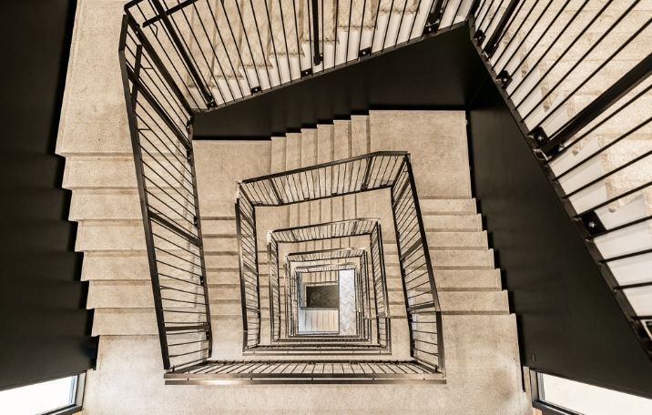 Indkørsel til nyopført kontorejendom med moderne spiraltrappe og gulvbelægning i marmor