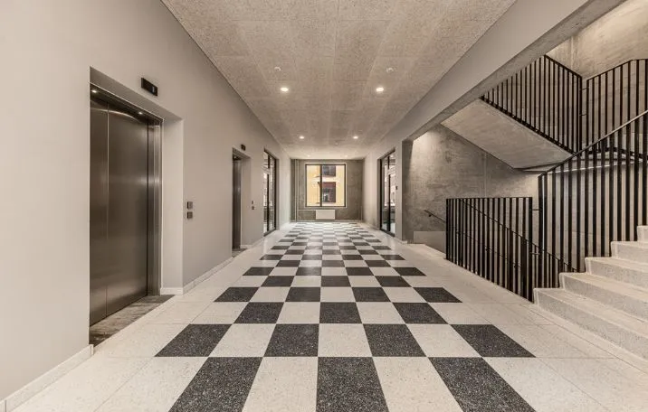 Kontorforretning med elevator og trapper til 4. og 5. sal med sjakk-mønstret gulv og moderne design