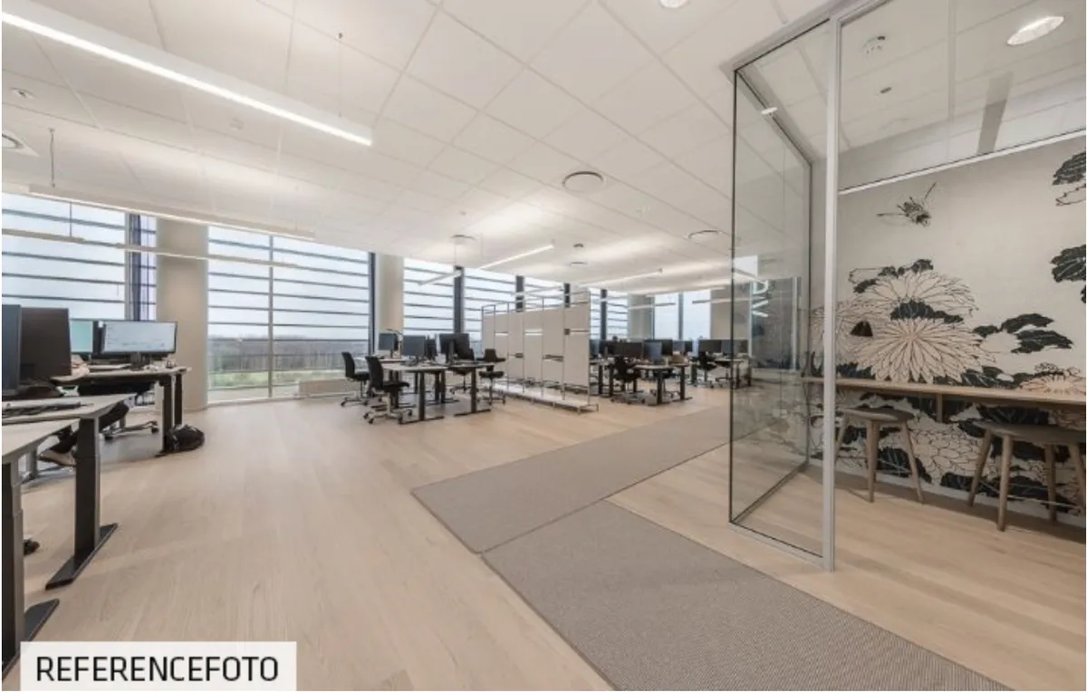 Moderne kontor med lyse lofter og gulve, skriveborde med computere, skyggefulde områder og smukke udsigtsvinkler til byen